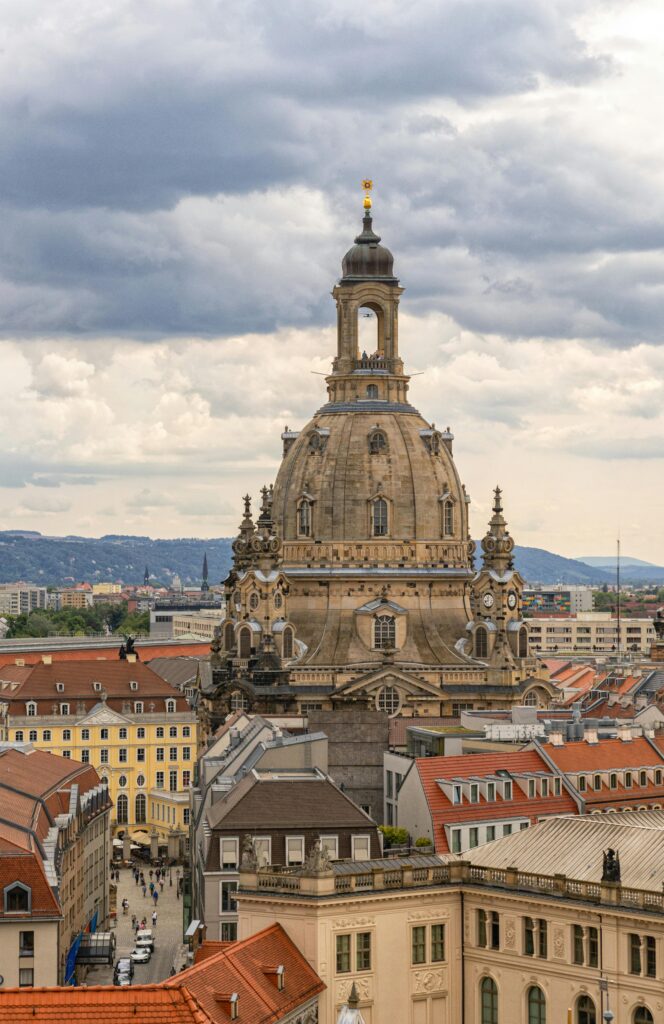 A stunning aerial view of the Frauenkirche in Dresden, showcasing Baroque architecture amidst city buildings under a cloudy sky.